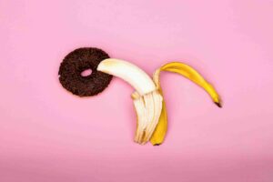 Photo of a peeled banana lying provocatively on a chocolate donut hole to imply anal sex