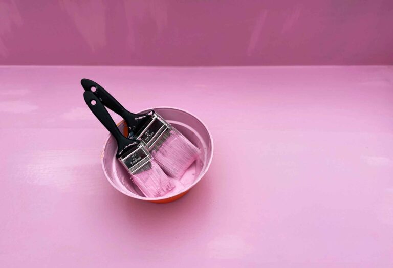 Two pink paintbrushes side by side on a pink background