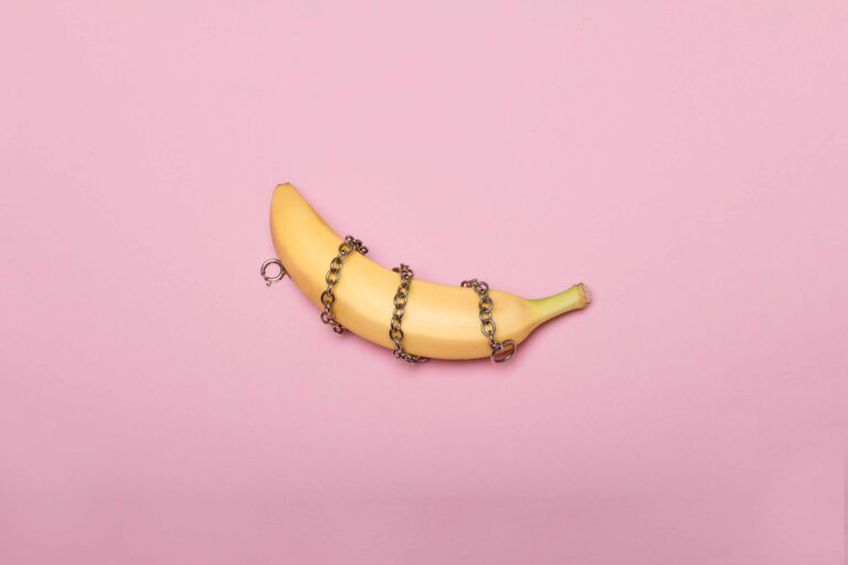 how to talk to your partner about kinks and fetishes - Pink background with a banana in chains