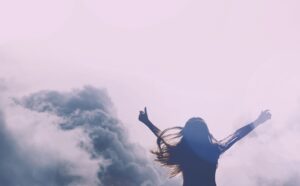 Photo of a woman infront of mountains and clouds feeling free and unburdened