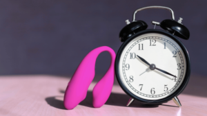 Photo of a clock and a sex toy to depict the importance of scheduling regular self-pleasure to enhance our mental well-being