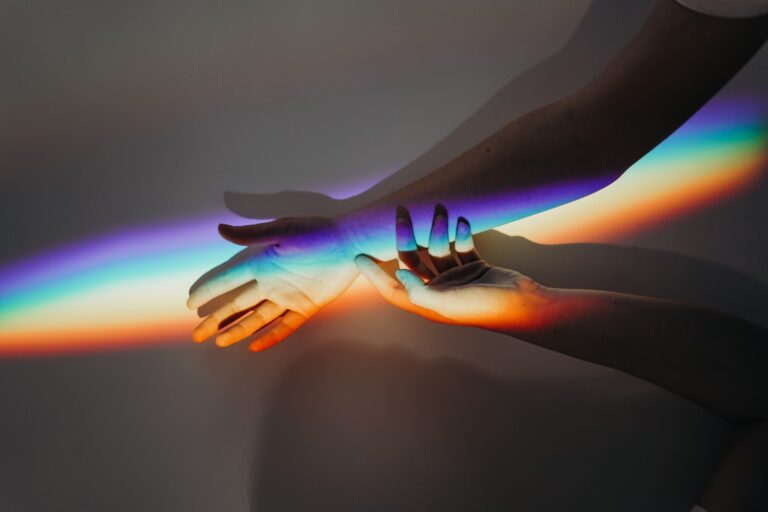 Photo of two hands in a sexual flow with rainbow lights to depict the article describing "sexual flow" by Lisa Opel for pleasepinchmehard