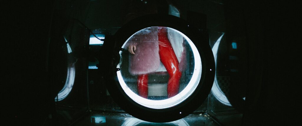 Photo of a person in red PVC trousers through a camera lens