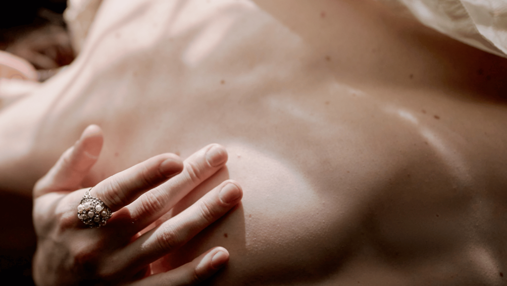 Photo of a woman's torso with her hand touching her skin.