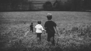 A photo of children running carefree down a hill in black and white.