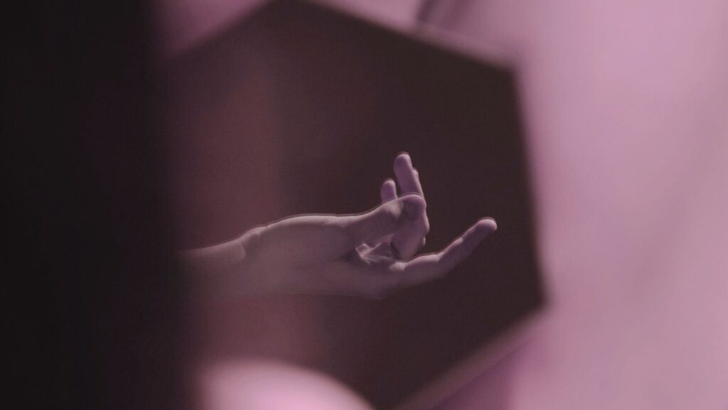 A hand suggestively in a mirror, fingers slightly spread, capturing a moment of intimacy and reflection.